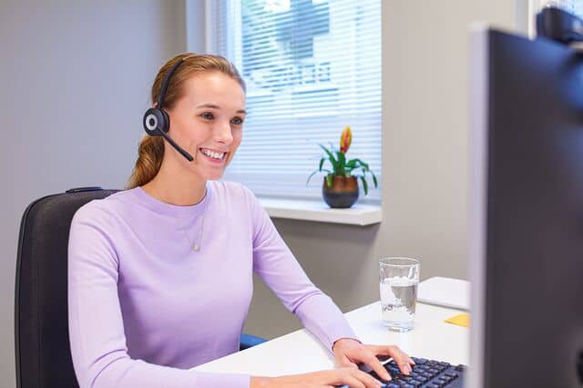Klantenservicemedewerker met telefoon aan haar oor